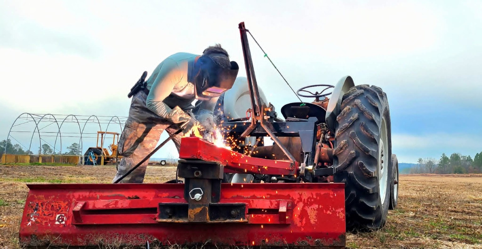 Repair work being completed on farm equipment beside the Ford tractor